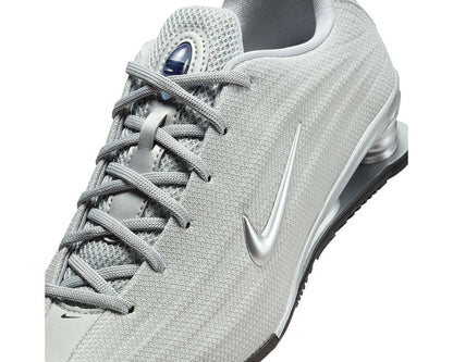 Scarpe sportive argentate con sistema di ammortizzazione a colonne.